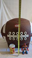Front view of the football toy chest with a measuring tape showing height approximately 21.5 inches. Includes a Play-Doh can and toy figure for scale.