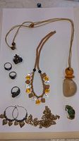 Photo showing the mixed jewelry items arranged on a white background including necklaces, rings, earrings, and pendants.