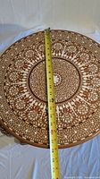 Close-up photo showing diameter measurement of the round tabletop with detailed floral inlay pattern.
