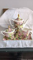 Full view of the tea pot set showing the tea pot, sugar bowl, creamer, and tray with floral pattern and gold accents.