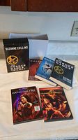 Photo of the three paperback books of The Hunger Games Trilogy and the two DVDs: The Hunger Games and Catching Fire.