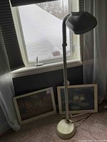 Overall lot with two framed Monet prints on floor leaning against wall and an adjustable beige Bell Howell floor lamp next to them.