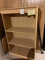 Light solid wood bookshelf with three shelves, showing the overall structure and condition.