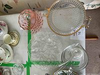 Top view of collectible glass dish set showing Loganberry pattern dish, bubble glass plate with gold handles, peach colored pressed glass dish, and clear gravy boat with ladle