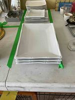 Four large rectangular white porcelain plates stacked.