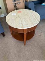 Front angled view of the Italian round side table showing the marble top, wooden base, legs and lower shelf.