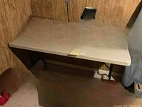 Large rectangular beige table with foldable legs against wooden wall