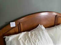 Close-up of the curved arched solid cherry wood headboard with detail and label.