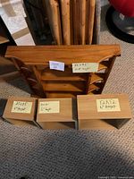 Photo showing four wooden shelving pieces on carpeted floor, including three floating cube box shelves with labeled dimensions and one larger wall hanging shelf.