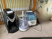 Three small kitchen appliances photo including Braun food processor, coffee maker, and humidifier together on carpet.