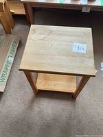Top down view showing the square tabletop surface with some visible water stains or discoloration, the lower shelf, and legs of the table.