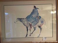 Framed watercolour print showing a woman in a blue dress on a horse, titled 'Woman Who Sees Farther', signed by Carol Grigg, in a light wood frame with glass.