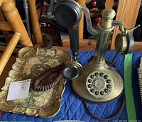 Photo showing the full candlestick phone and decorative tray from a side angle, emphasizing the engraved details and condition.