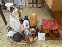 Overview of mixed home décor arts and trinkets lot including fabric doll, wooden giraffe, nesting dolls, small ceramics, and wooden miniature house