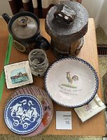 Photo showing all ceramic pieces including teapot, plates, candle holders, and carved wooden container on table.