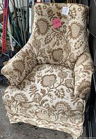 Front view of the club armchair showing the beige fabric with floral and heart-shaped brown pattern upholstery.