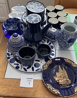 Overhead view of blue and white dinnerware set including teapot, mugs, saucers, plates, decorative plate and vase