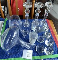 Wide shot of 19 crystal and glassware pieces on padded surface including candlesticks, vase, bowls, and glasses