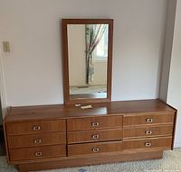 Front view of vintage solid wood dresser with 9 drawers and attached rectangular mirror.