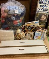 Front overview showing sealed bag of yarn, craft kits, embroidery hoops, storage cubes and two Singer machine boxes