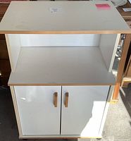 Front view of the microwave stand showing top, middle shelf and closed cabinet doors below.