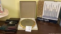 Photo showing 6 women's wallets in various colors, a solid brass round photo frame in original Bronx box, and a boxed candlelight set