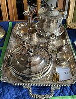 Full view of the entire silver-plated tea and serving set arranged on the ornate serving tray, showing all items including teapot, covered dish, creamer, sugar bowl, candle holders.