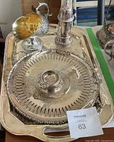 Photo showing the six silver plated items arranged on the large tray, highlighting the pitcher shaped like a bird, pepper shaker, gold interior bowl, round platter with strainer, and tray handles.