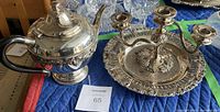Silver tea set consisting of teapot, candelabra, and serving tray on a blue padded surface with lot number card visible.