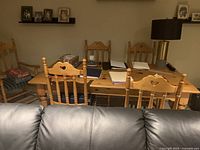 Rectangular solid pine dining table viewed from the end with six matching chairs and green cushions, natural wood finish with visible grain and knots.