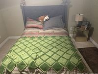 Fully made twin bed with dark grey tufted headboard, pillows and blankets shown to illustrate style and color