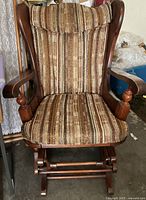 Front view of vintage glider rocking chair showing wooden frame and striped tweed upholstery.