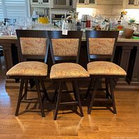Front view of three chairs lined up on hardwood floor in front of kitchen island