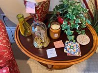 Photo of round solid wood end table with various home decor items including a lamp, clock, vase and plants on top