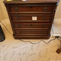 Front view of cabinet showing three drawers with brass-tone ring pulls and mahogany finish