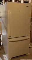 White Whirlpool bottom freezer refrigerator showing front and side profile