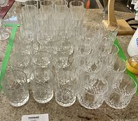 22 crystal tumblers seen from above, showing cut glass patterns and thick bases on a countertop.