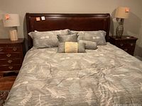 Front view of assembled sleigh bed frame with mattress, comforter and decorative pillows