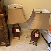 Both lamps side by side showing full bodies, shades and bases next to wooden cabinet.