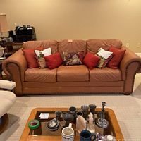 Front view of three-seat sofa with six decorative pillows and coffee table in foreground