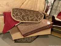Stack of various rugs in different sizes and colors with floral and traditional patterns.