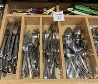 Close-up of forks, knives, and spoons laid out in organizer compartments, showing quantity and condition.