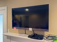 Front view of Sony Bravia TV mounted above mantel with Philips Blu-ray player and cables on shelf