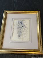 Framed print of a female form study with gold-colored frame and beige matting.