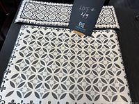 Top view of floor mat and table runner showing patterns and colors, black hardwood floor background