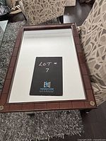 Top view of the rectangular mirror showing wood frame with brass corner details and clear mirror surface.