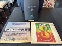 Photo showing both vinyl album covers, The Mamas & The Papas and Hair, with a black folder labeled Lot #55 in the background.