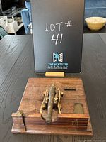Top view of the brass cannon model mounted on a wooden platform base showing the entire model and the wood grain.