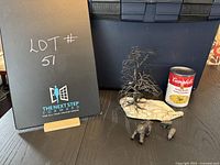 Photo shows the lot containing the metal tree sculpture mounted on a stone base, three miniature brass bear figurines, and a can for scale reference.