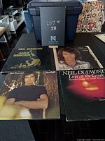 Four Neil Diamond vinyl records lying on table showing cover art for albums Jazz Singer, Moods, Heartlight, and Love at the Greek